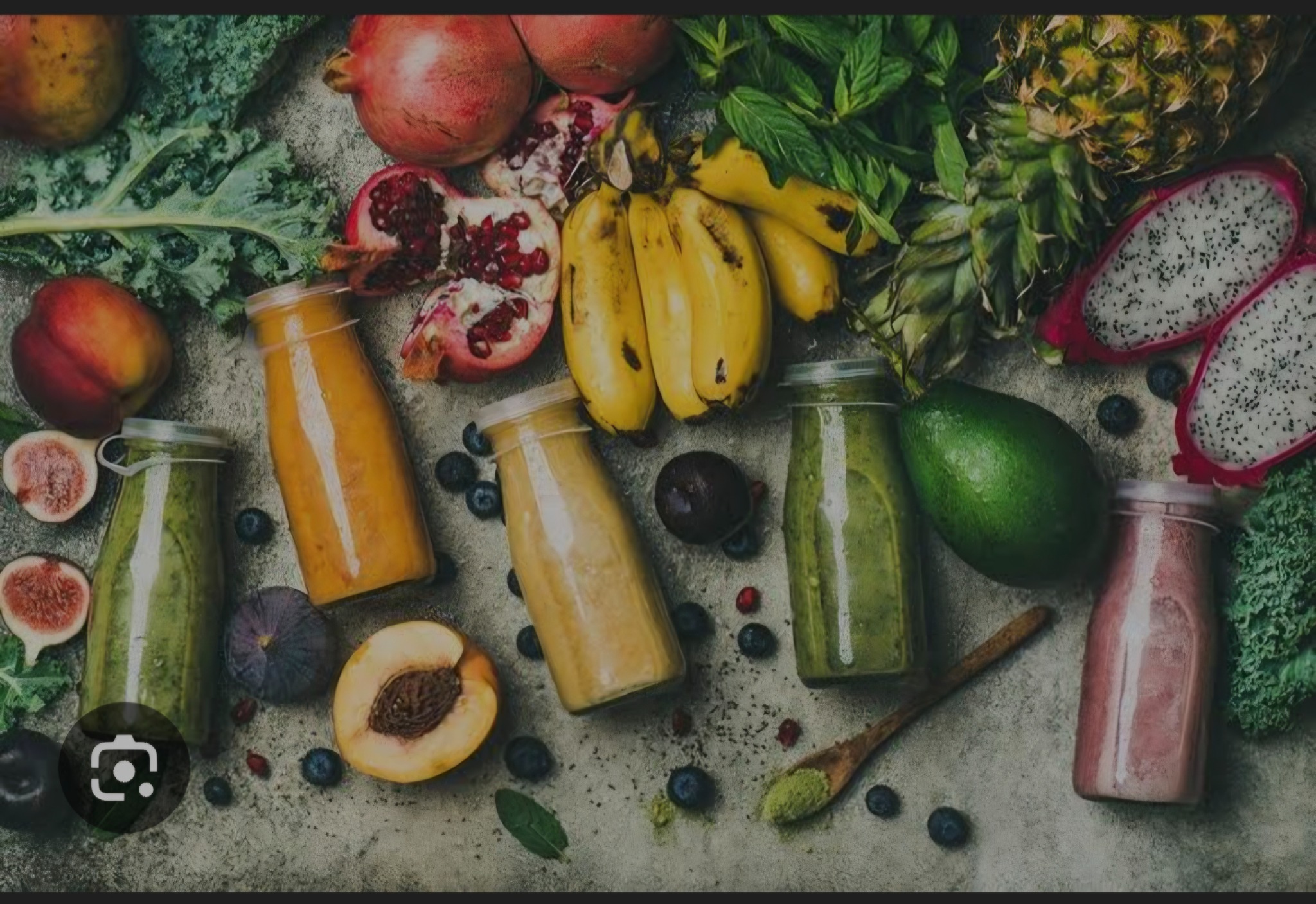 Fresh colourful juices surrounded by fruits and greens